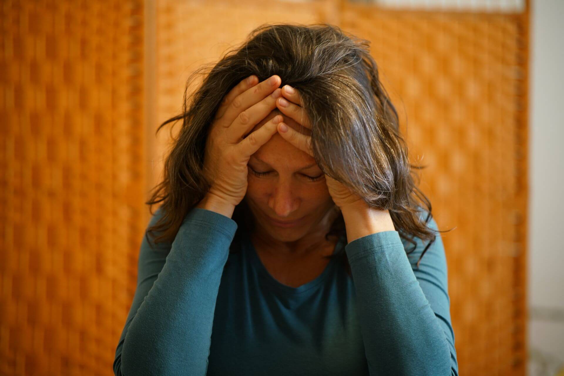 Person stützt Kopf in die Hände – Symbolbild für seelische Belastung
